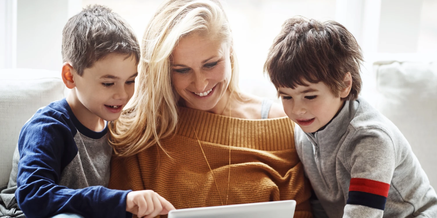 Mutter und zwei Kinder schauen gemeinsam auf Tablet.