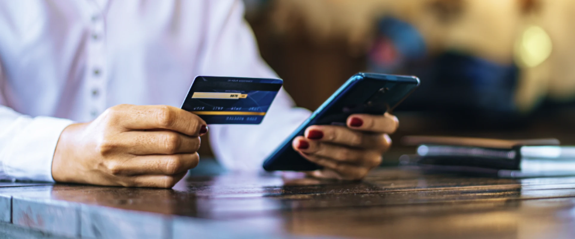 Woman holding smartphone in one hand and loyalty card in the other.