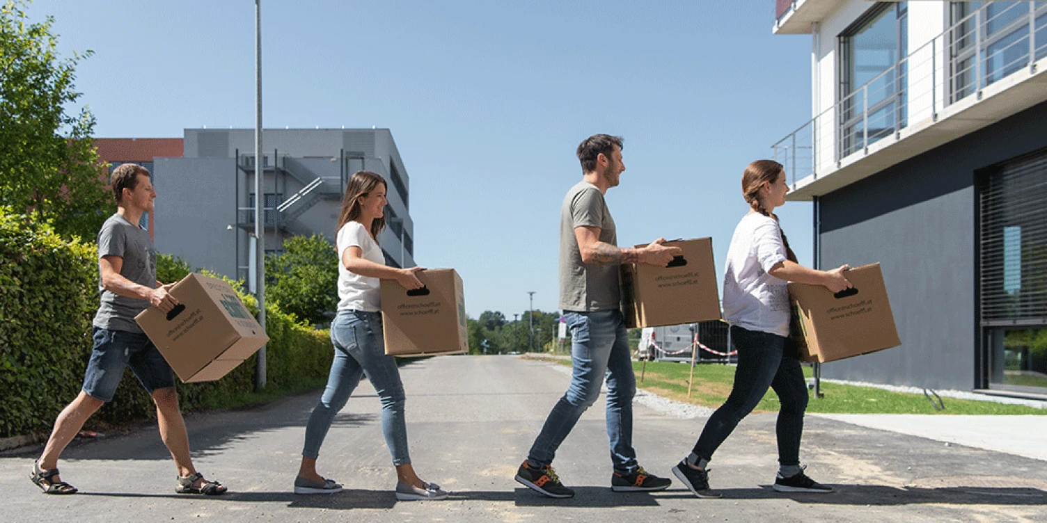 Mitarbeiter*innen tragen Umzugskartons in das neue Büro im Business Campus One.