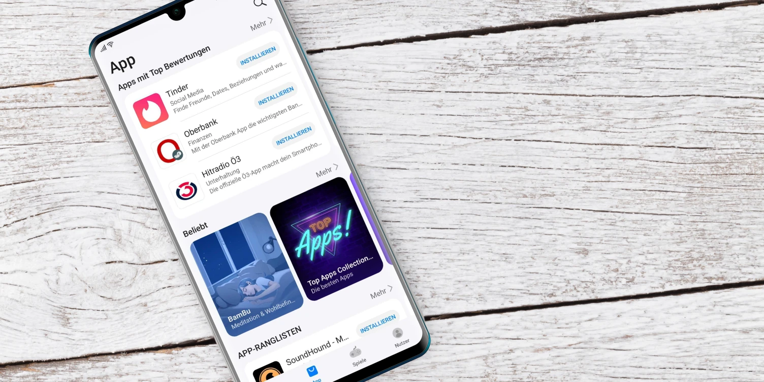 Smartphone mit geöffnetem Appstore liegt auf Holz-Untergrund.