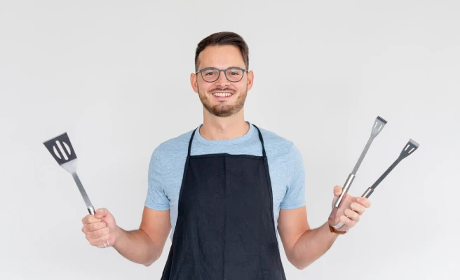 Employee Daniele Satta with apron and cooking tongs