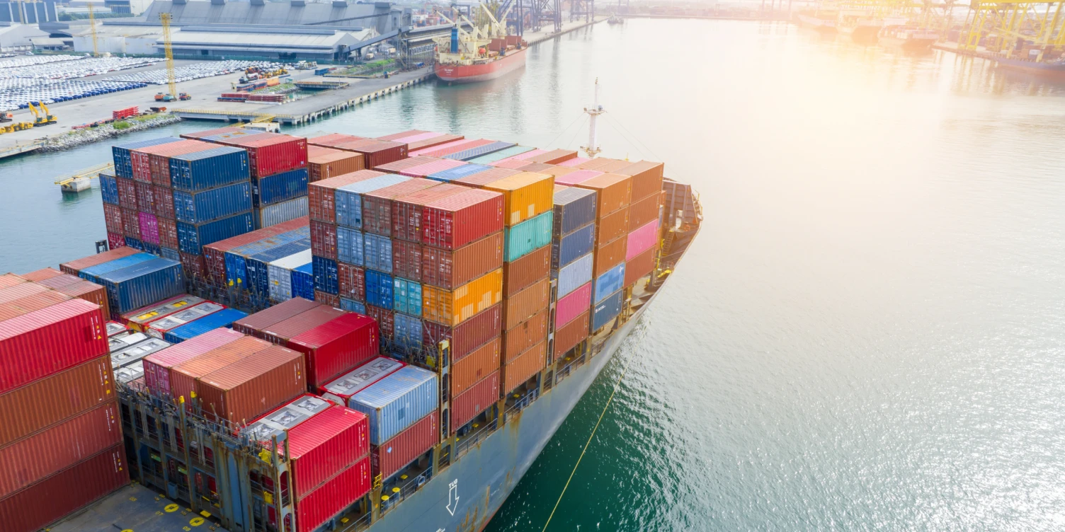 Voll beladenes Containerschiff fährt aus dem Hafen.