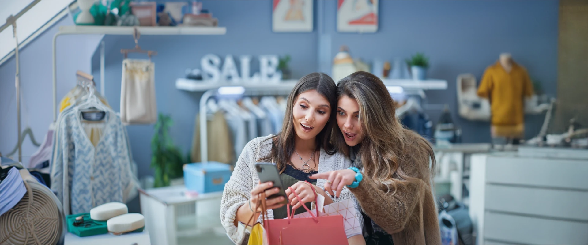 Zwei Frauen, die freudig erstaunt darüber sind, was sie auf einem Smartphone sehen.