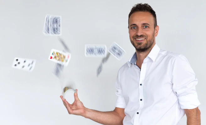 Mitarbeiter Josef Rieseneder schleudert Spielkarten in die Luft.