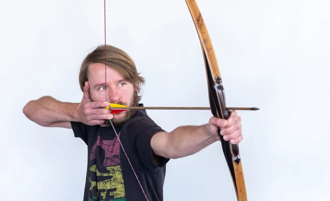 Mitarbeiter Maik Hering schießt mit Pfeil und Bogen