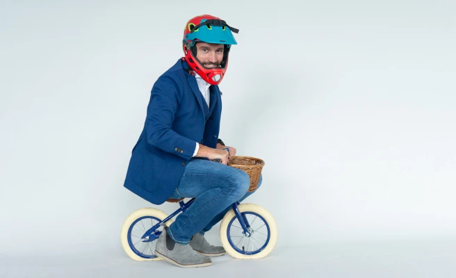 Mitarbeiter Oliver Hartl trägt Helm und sitzt auf Kinderfahrrad.