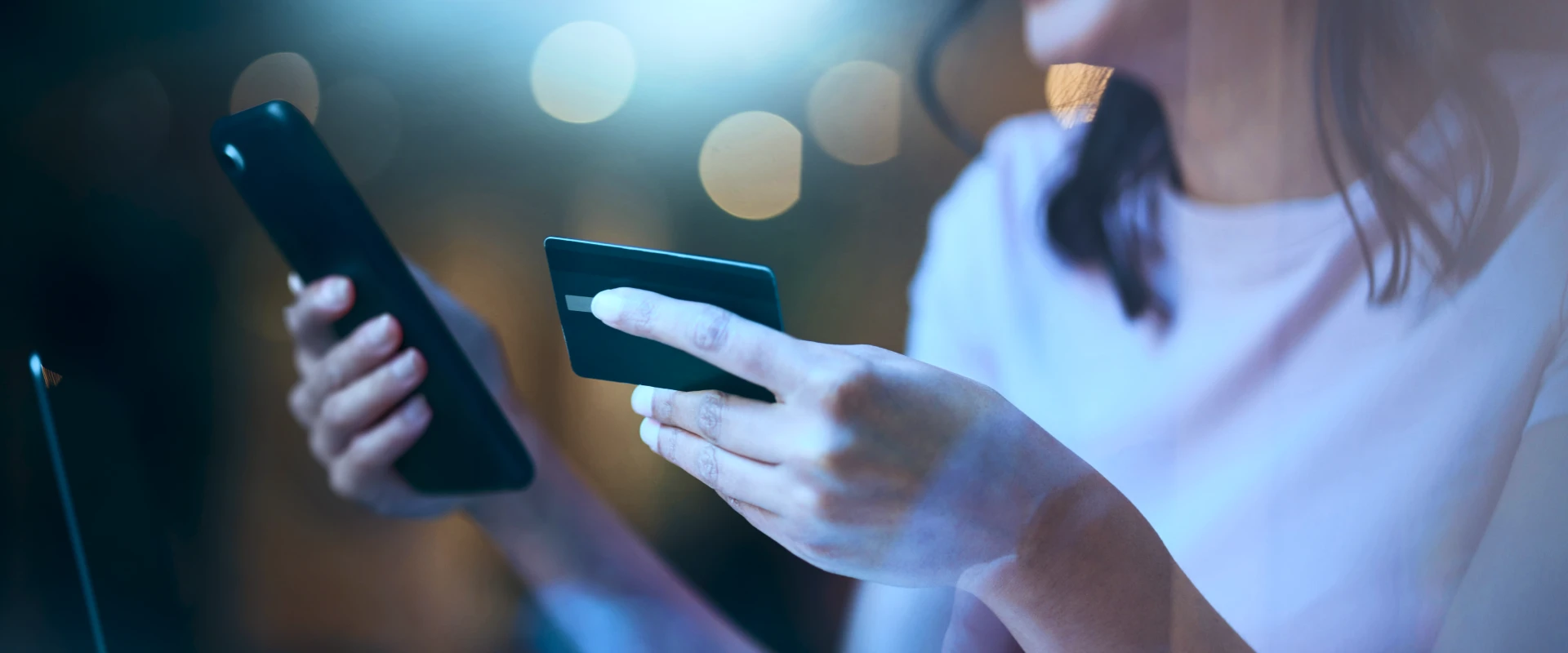 Woman holding smartphone in one hand and customer card in the other.