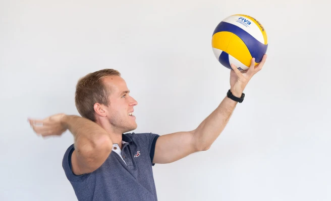 Mitarbeiter Rene Windischhofer spielt einen Volleyball.