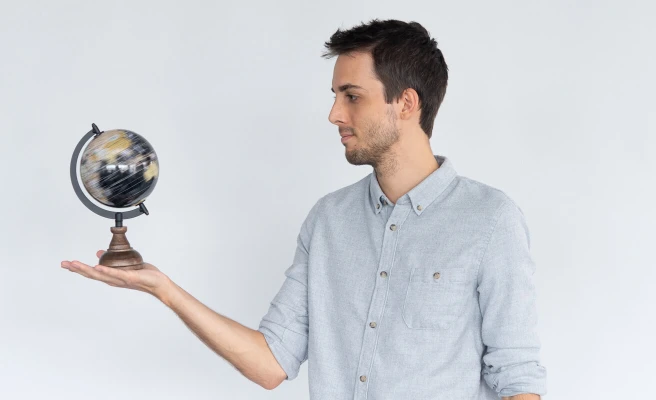 Employee Thomas Kranzer holds a small globe in his hand.