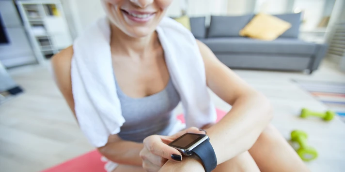 Frau in Fitness-Outfit drückt auf die Smartwatch an ihrem Handgelenk.