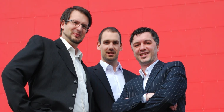 Roland Sprengseis, Martin Sprengseis and Wolfgang Stockner in front of a red background.