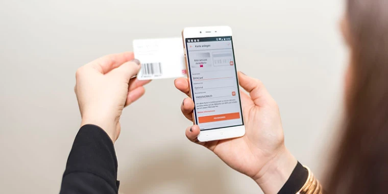 Woman holds smartphone with mobile-pocket app and digitalizes customer card.