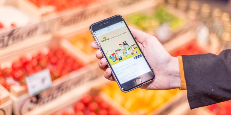 Hand with smartphone and offer in the mobile-pocket app in a store.