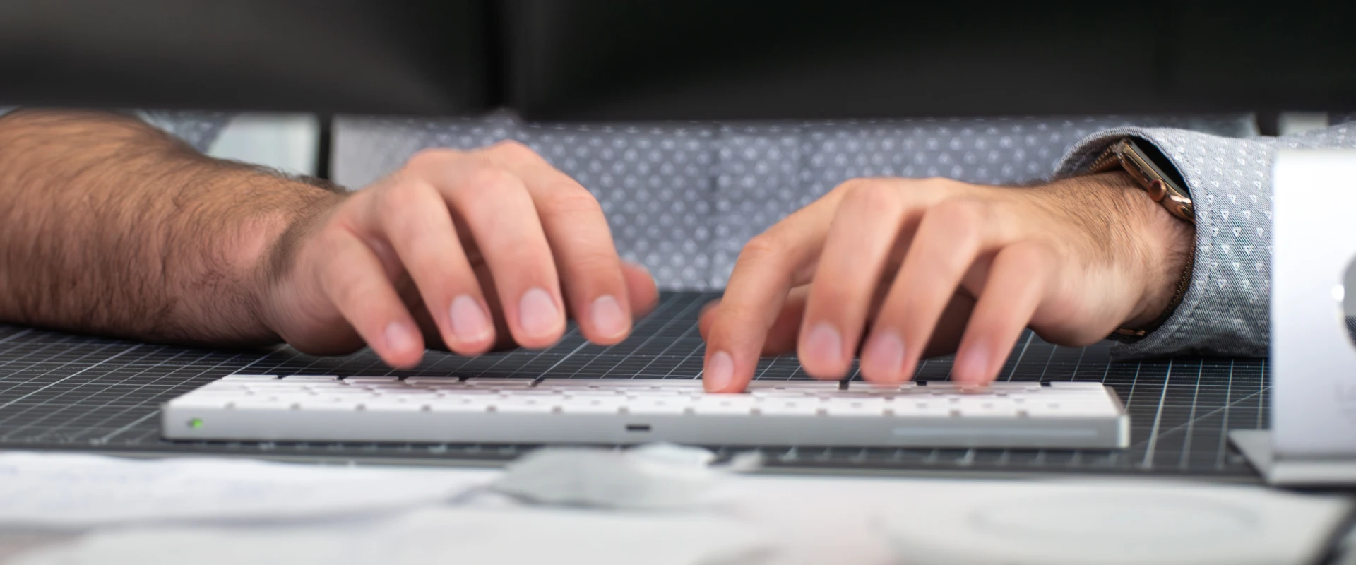 Durchsicht unter Bildschirm auf zwei Männerhände, die auf Computertastatur schreiben.