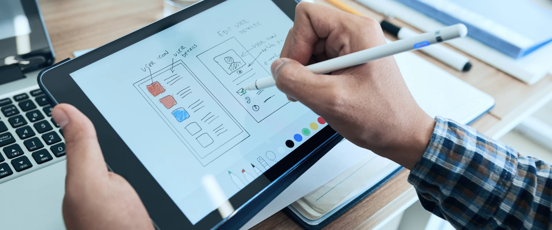 Man sketching the design of an app screen with a pen on a tablet.