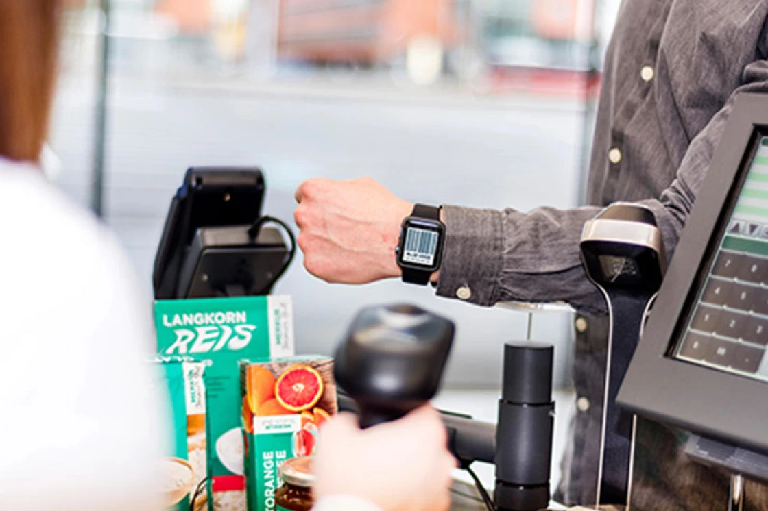 Bezahlung mit Bluecode per Smartwatch an der Kasse eines Lebensmittelhändlers.