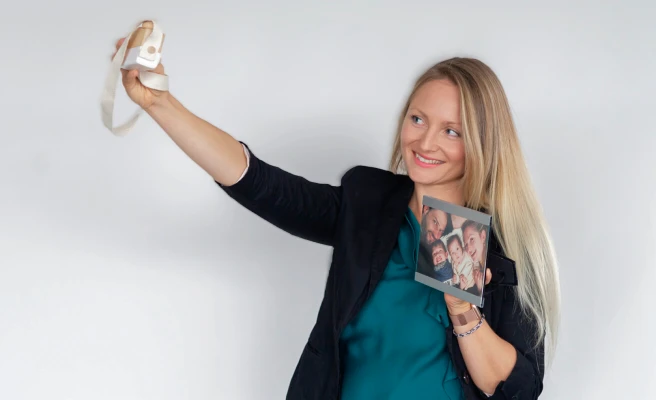 Mitarbeiterin Ines Madlsperger mit einer Kamera und einem Familienfoto in der Hand.