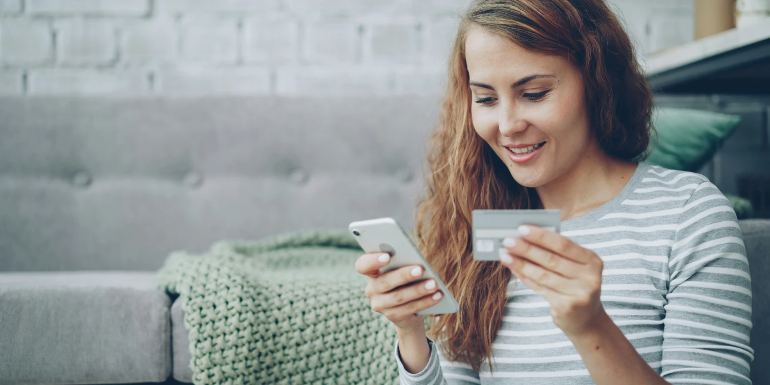 Kundin nutzt Smartphone und Bankkarte für Mobile Banking App und Neobank-Services